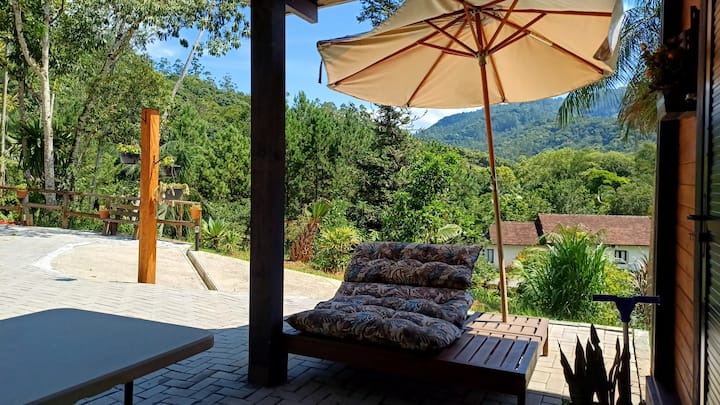 Mesa externa sob guarda-sol na área de lazer da cabana